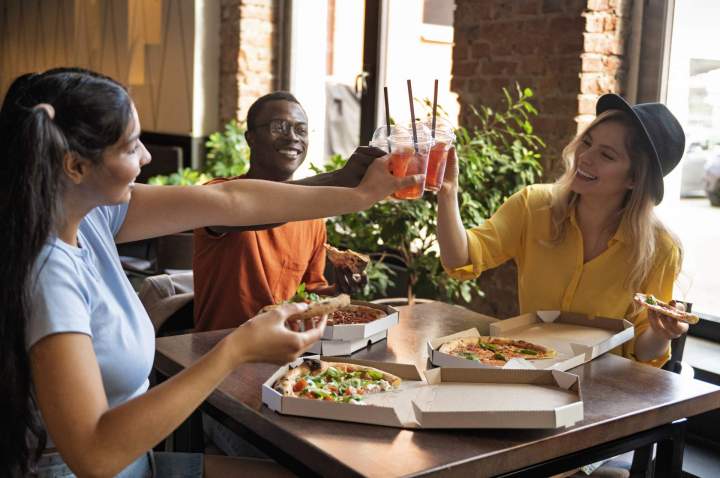 medium shot friends eating pizza
